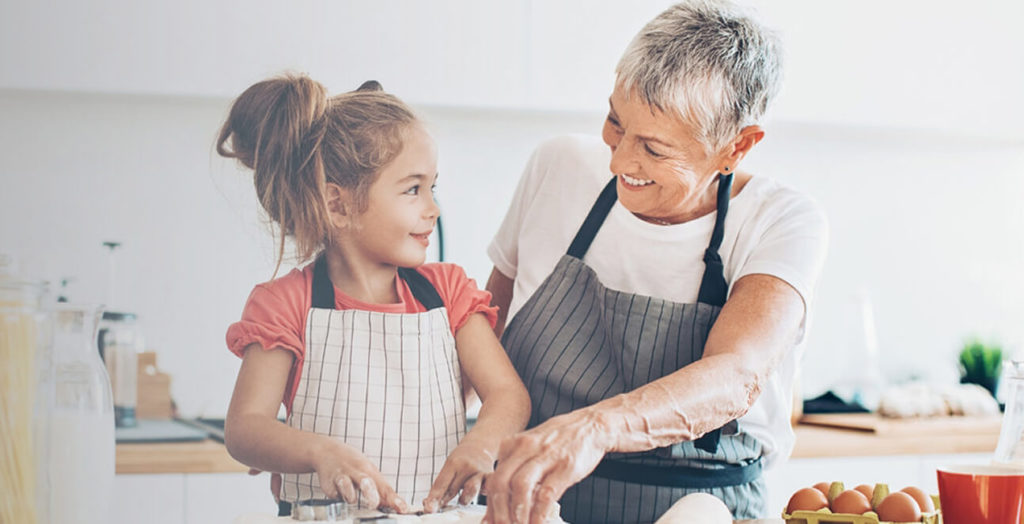 Grandmother making food with granddaughter